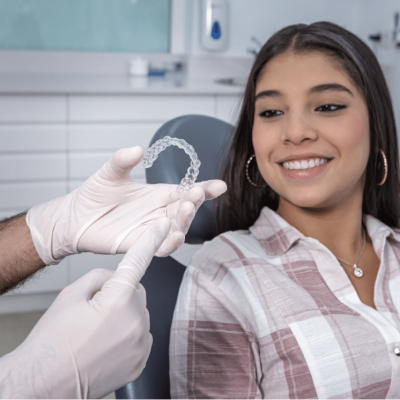 Young girl is being shown aligners by her orthodontist. She is smiling