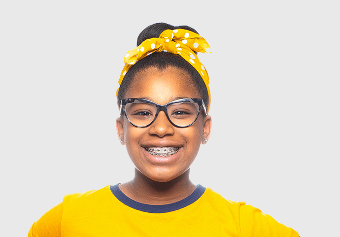 Vibrant girl with metal braces smiling in glasses, a yellow shirt, and yellow bandana