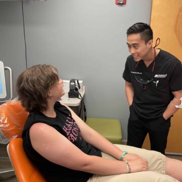 Dr. Ha stands in front of a patient he is consulting with