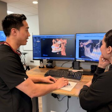 Dr. Ha stands at a desk with a member of the staff